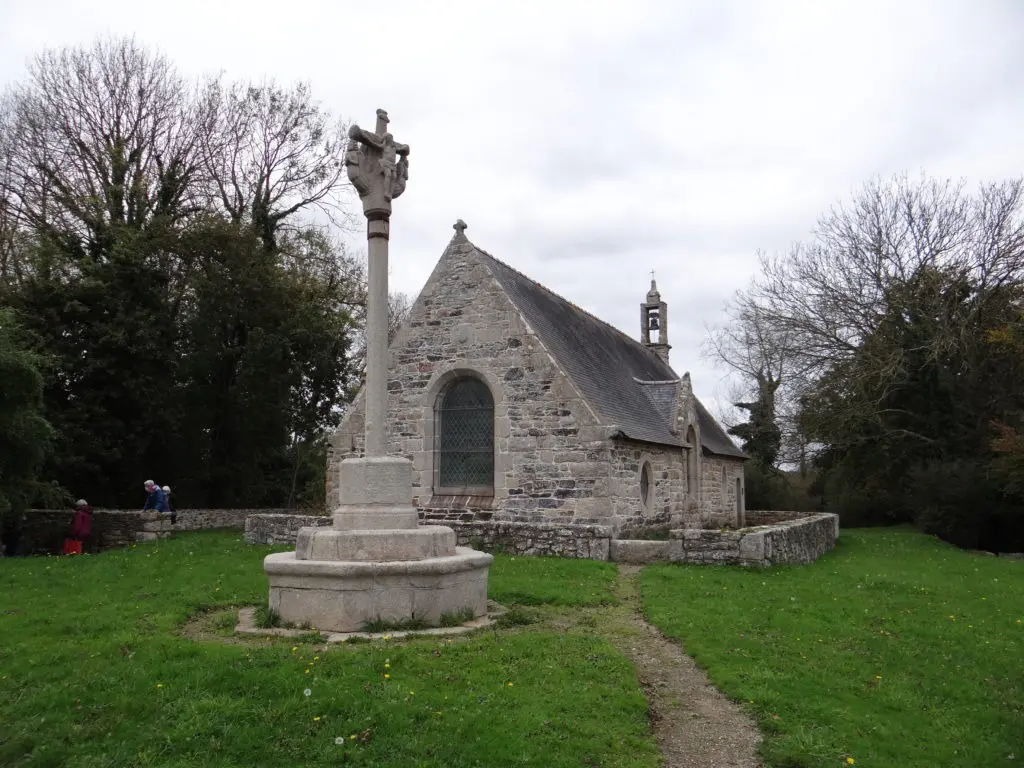Chapelle bretonne en pierre avec son calvaire dans un enclos paroissial.